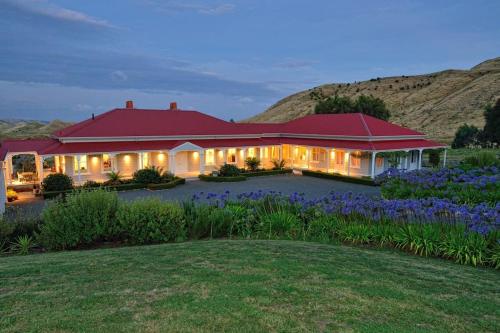 a house with a red roof with purple flowers at Cape South Estate - International award-winning country estate with Pacific views in Havelock North