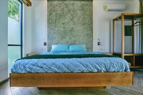 a bedroom with a large bed with blue pillows at Villas Zamna - Jungle Villas in Cozumel
