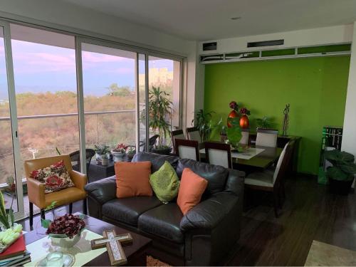a living room with a couch and a dining room with green walls at Depa Centro Culiacán in Humaya