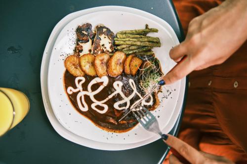 a person holding a plate of food with meat and asparagus at Villas Zamna - Jungle Villas in Cozumel