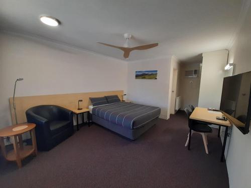 a bedroom with a bed and a chair and a television at Cooma Motor Lodge Motel in Cooma