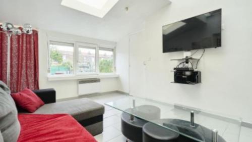 a living room with a couch and a tv on the wall at Spacieuse maison avec chambres et salle de bain privées en colocation à 10 min de Lille in Lille