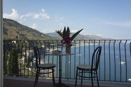 a table and chairs on a balcony with a view of the water at Bay Palace Mazzarò in Taormina