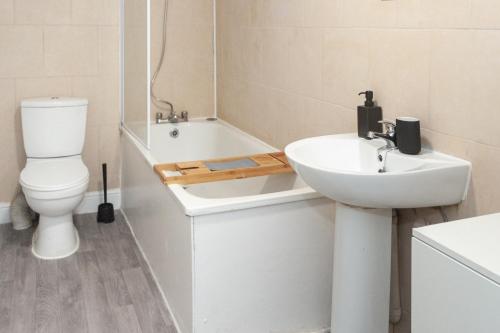 a bathroom with a sink and a toilet and a tub at Modern 1BR Haven Central Croydon in Croydon