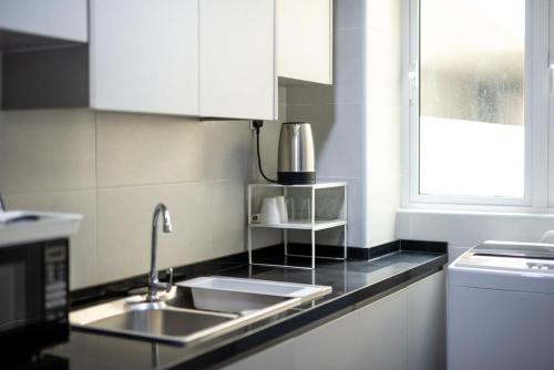 a kitchen with white cabinets and a sink and a window at Comfy 3BR Apt @ KSL Daya Near IKEA Tebrau Parking in Johor Bahru