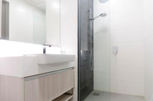 een witte badkamer met een wastafel en een douche bij A Comfy & Cozy Suasana Suites in Johor Bahru in Johor Bahru