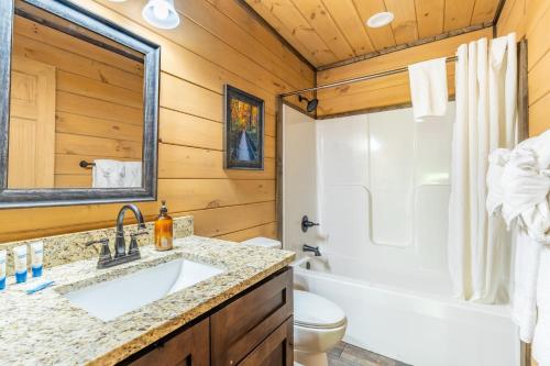 ein Badezimmer mit einem Waschbecken, einer Badewanne und einem WC in der Unterkunft The Wacky Woodpecker by AvantStay Game Room Private Hot Tub Pool Access in Pigeon Forge