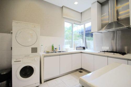 a white kitchen with a washing machine in it at A Spacious & Lux 4BR House with Gazebo in Cheras