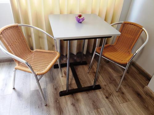 einem weißen Tisch mit zwei Stühlen und einer Vase darauf in der Unterkunft Hostal Ñan Tika in Sicuani
