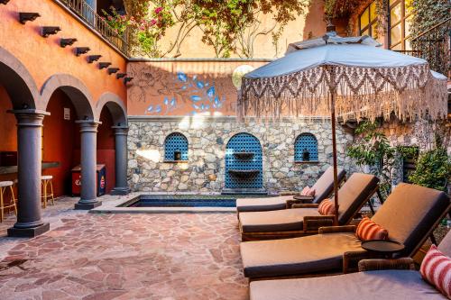 an outdoor patio with chairs and an umbrella at Casa Almira 5BR Luxury Home with Pool, Hot Tub & Rooftop in San Miguel de Allende