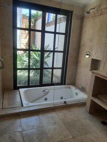 y baño con bañera y ventana grande. en Quinta Edén Cuernavaca en Cuernavaca