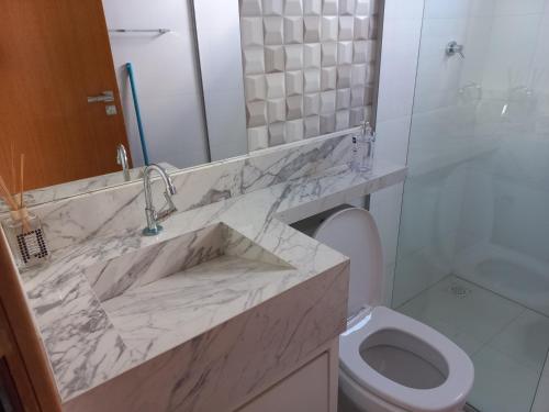 La salle de bains est pourvue d'un lavabo en marbre et de toilettes. dans l'établissement apartamento studio setor Sul, à Palmas