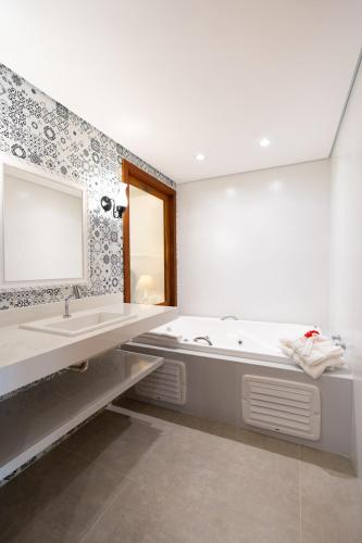 a bathroom with a tub and a sink and a mirror at Resende Imperial Hotel & Spa in Itacaré