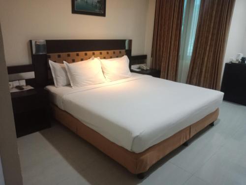een bed met witte lakens en kussens in een kamer bij Manise Hotel in Ambon