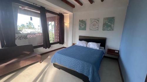 a bedroom with a blue bed and a window at Juanchos House Hostel Tayrona in Los Naranjos