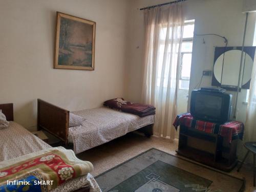Habitación con cama, TV y espejo. en Al Amawi Hostel en Amán
