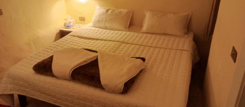a bedroom with a bed with white sheets and pillows at Dana Gardens Hotel in Dana