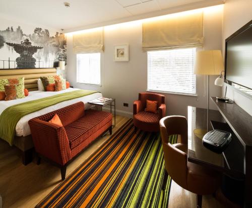 une chambre d'hôtel avec un lit et deux chaises dans l'établissement Hotel Indigo London Hyde Park Paddington, an IHG Hotel, à Londres