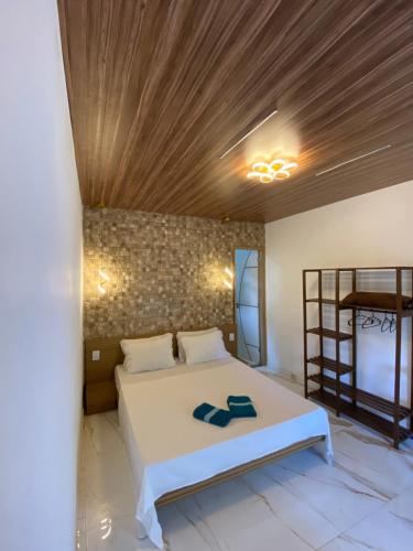 a bedroom with a white bed with a wooden ceiling at • Suíte Palmas • À Beira-Mar - Ilha Grande RJ® in Praia de Palmas
