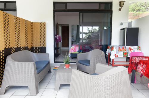un patio con sillas blancas de mimbre y una mesa en A TOMO MAI en Uturoa