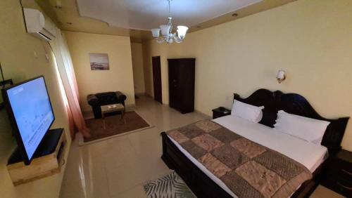 a bedroom with a bed and a flat screen tv at Kings Empire Hotel in Freetown