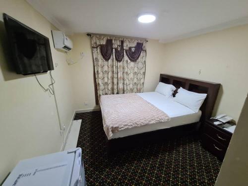 Habitación de hotel con cama y TV en Kings Empire Hotel en Freetown