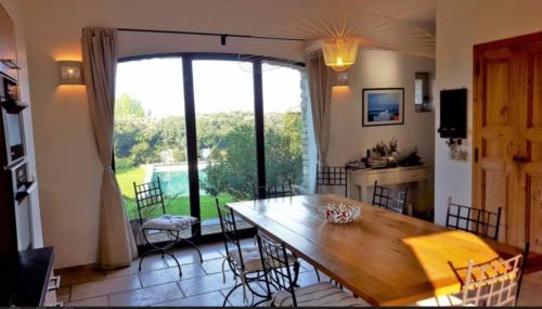 a dining room with a table and a large window at Superb air-conditioned house with heated pool in Gordes - by feelluxuryholydays in Gordes