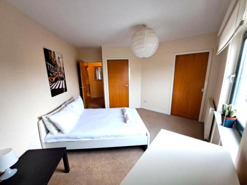 um quarto com uma cama branca e uma mesa em Modern 2 Bed Apartment Close to Gla Airport & M8 em Paisley