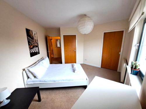 a bedroom with a white bed and a table at No 2 - Modern 2 Bed Apartment Close to Gla Airport & M8 in Paisley
