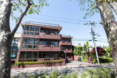 a brick building with trees in front of it at Mitte Misono Apartments in Sapporo