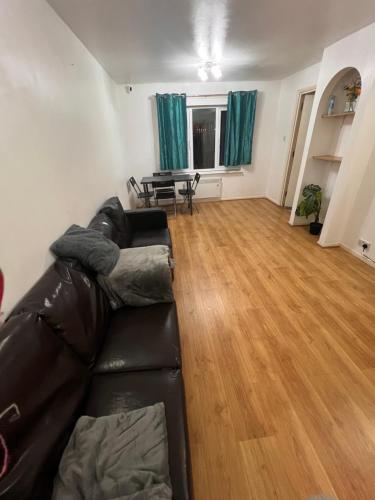 uma sala de estar com um sofá de couro e uma mesa em Cosey Croydon em South Norwood