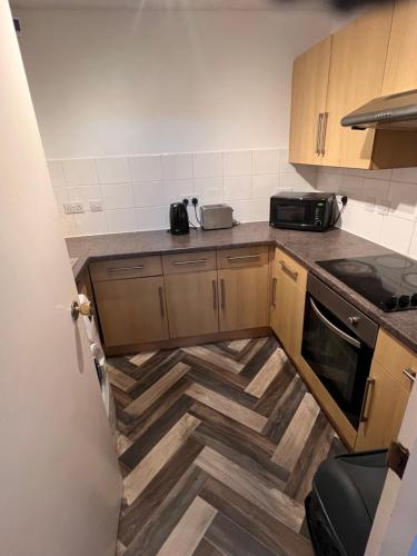 a kitchen with wooden cabinets and a wooden floor at Cosey Croydon in South Norwood