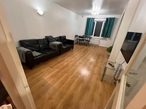 uma sala de estar com um sofá de couro preto e uma mesa em Cosey Croydon em South Norwood