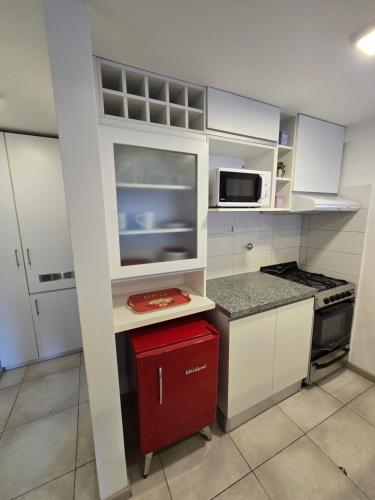 a small kitchen with white cabinets and a red drawer at Barrancas del Monumento con Parking privado opcional in Rosario