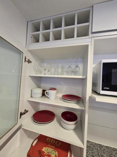 a white kitchen with red plates and a microwave at Barrancas del Monumento con Parking privado opcional in Rosario