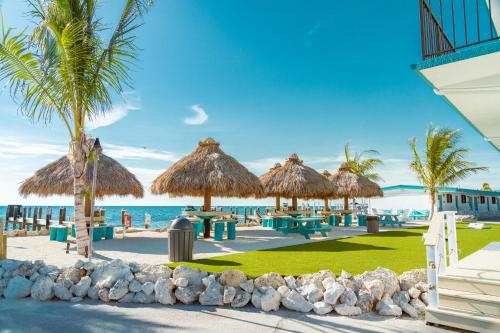 a resort with tables and straw umbrellas on the beach at Edgewater Lodge in Layton