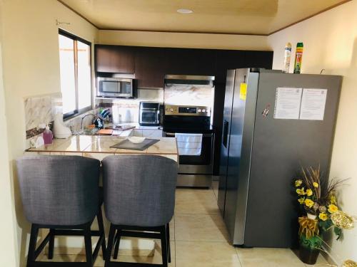 a kitchen with a refrigerator and two bar stools at Senderos Apartment, Self Check- in, Airport SJO 5 MIN in Santiago Este