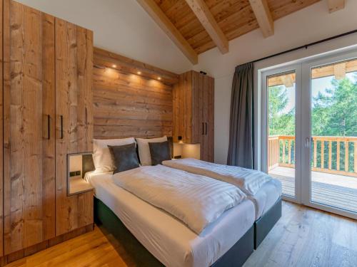 a bedroom with a large bed and a large window at Alpinchique 3 Mountain Chalet in Turracher Hohe
