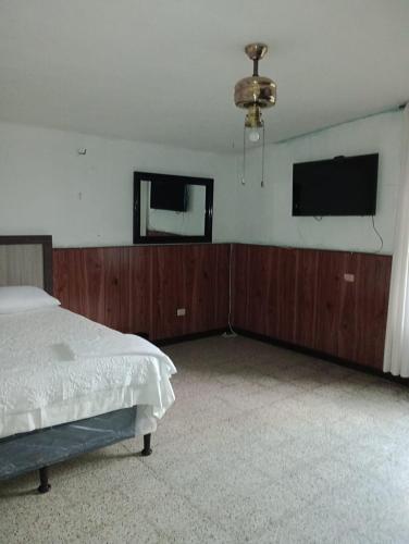 1 dormitorio con 1 cama y TV de pantalla plana en MUNDO HOSTAL, en Guatemala