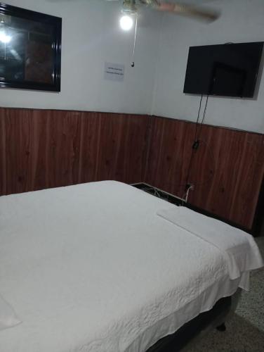 1 dormitorio con 1 cama blanca y TV de pantalla plana en MUNDO HOSTAL, en Guatemala