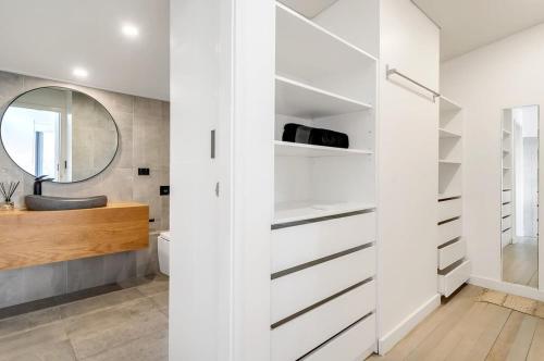 a bathroom with white cabinets and a mirror at Picture-Perfect Masterpiece In Mosman in Sydney