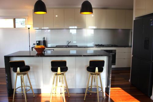 a kitchen with a counter with three bar stools at Buena Vista - Luxe 4 bedroom house, Views, Beach in Yeppoon