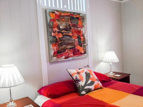 a bedroom with a bed with two lamps and a painting at West End Luxury 4B3B Home w Parking and Home Pod Music System M9 in Brisbane