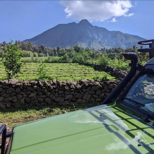 a green jeep parked in front of a field at Wildlife friendly safari in Bugesera