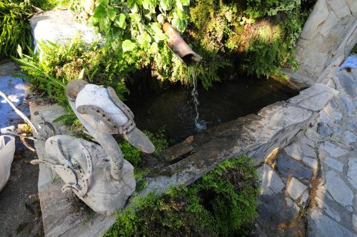 a stone statue of a water fountain next to a creek at Alojamiento Rural El Brazal in Lanjarón