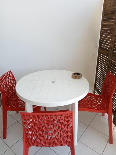 d'une table blanche entourée de deux chaises rouges. dans l'établissement Barbin's Seaview House, au Gosier