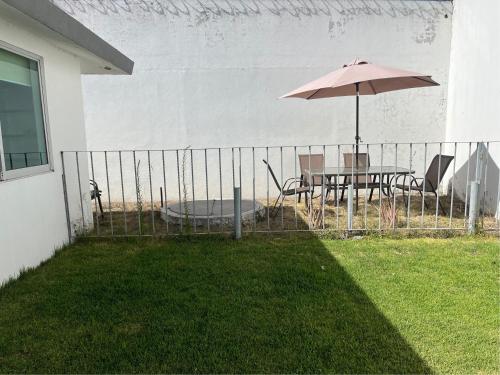 a table with an umbrella next to a fence with a table and chairs at La Casa del Agua Puebla in Acatepec