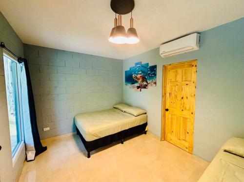 a small bedroom with a bed and a window at Hostal Camila’s in Tamanique