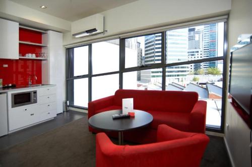 a living room with a red couch and a table at City Edge on Elizabeth Apartment Hotel in Melbourne