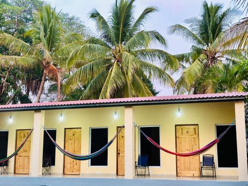 a house with hammocks in front of it with palm trees at Hostal Camila’s in Tamanique